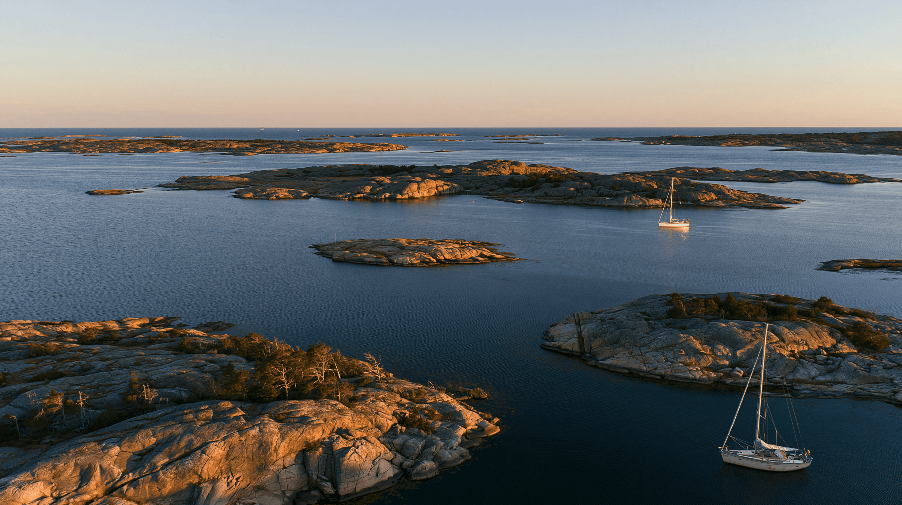 Flygfoto över skärgårdsöar med segelbåtar i stilla vatten