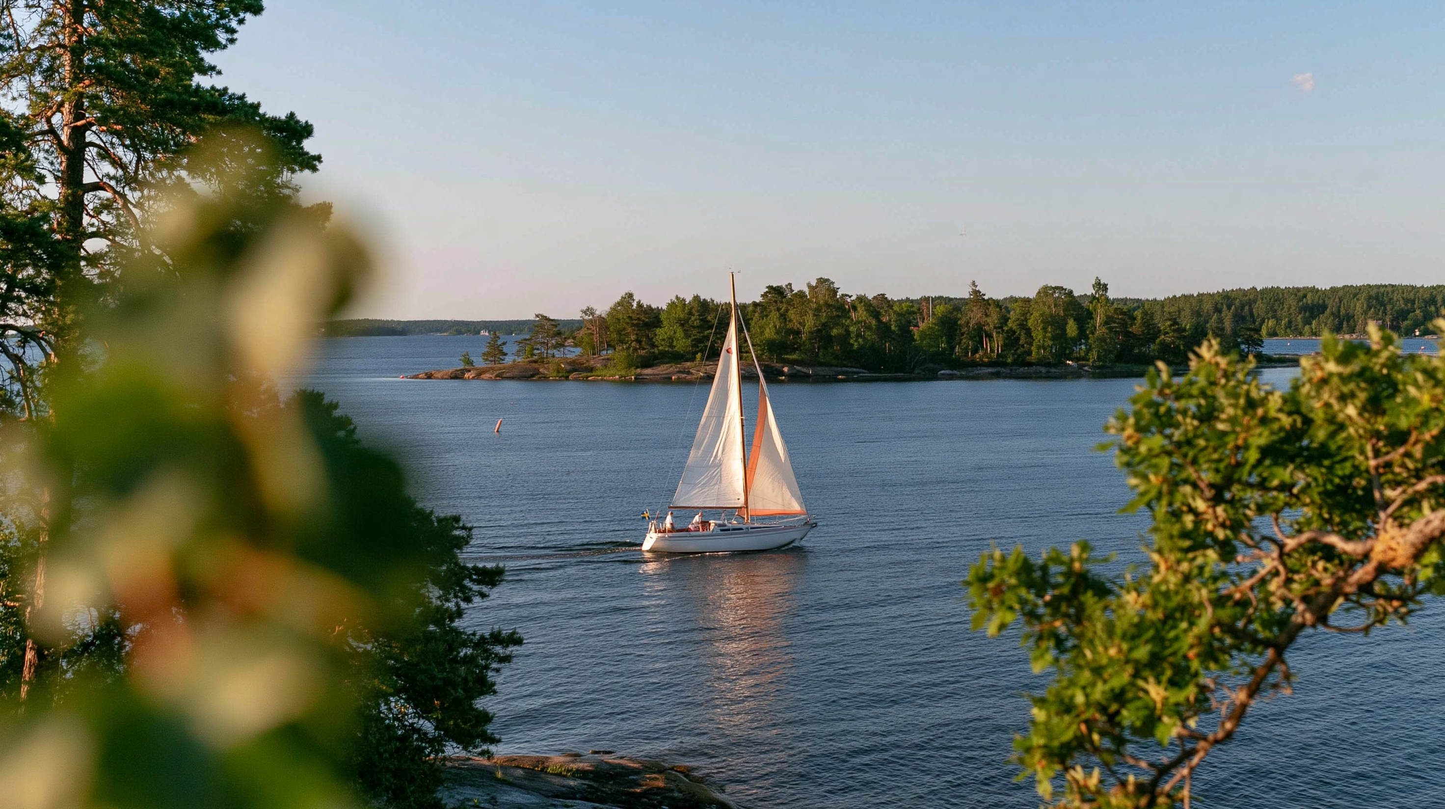 Segelbåt mellan träd i den svenska skärgården