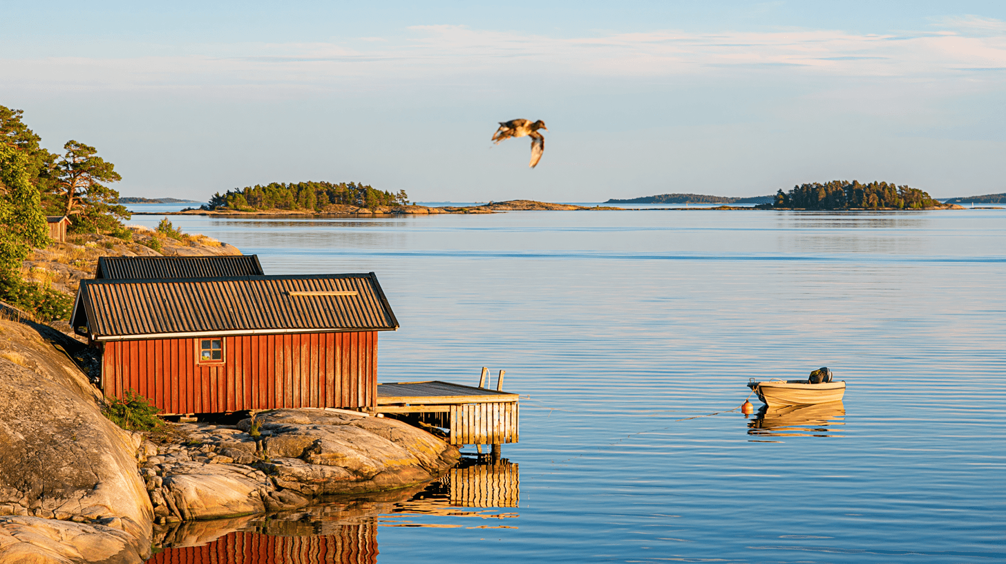 Rött båthus vid stilla skärgårdsvatten