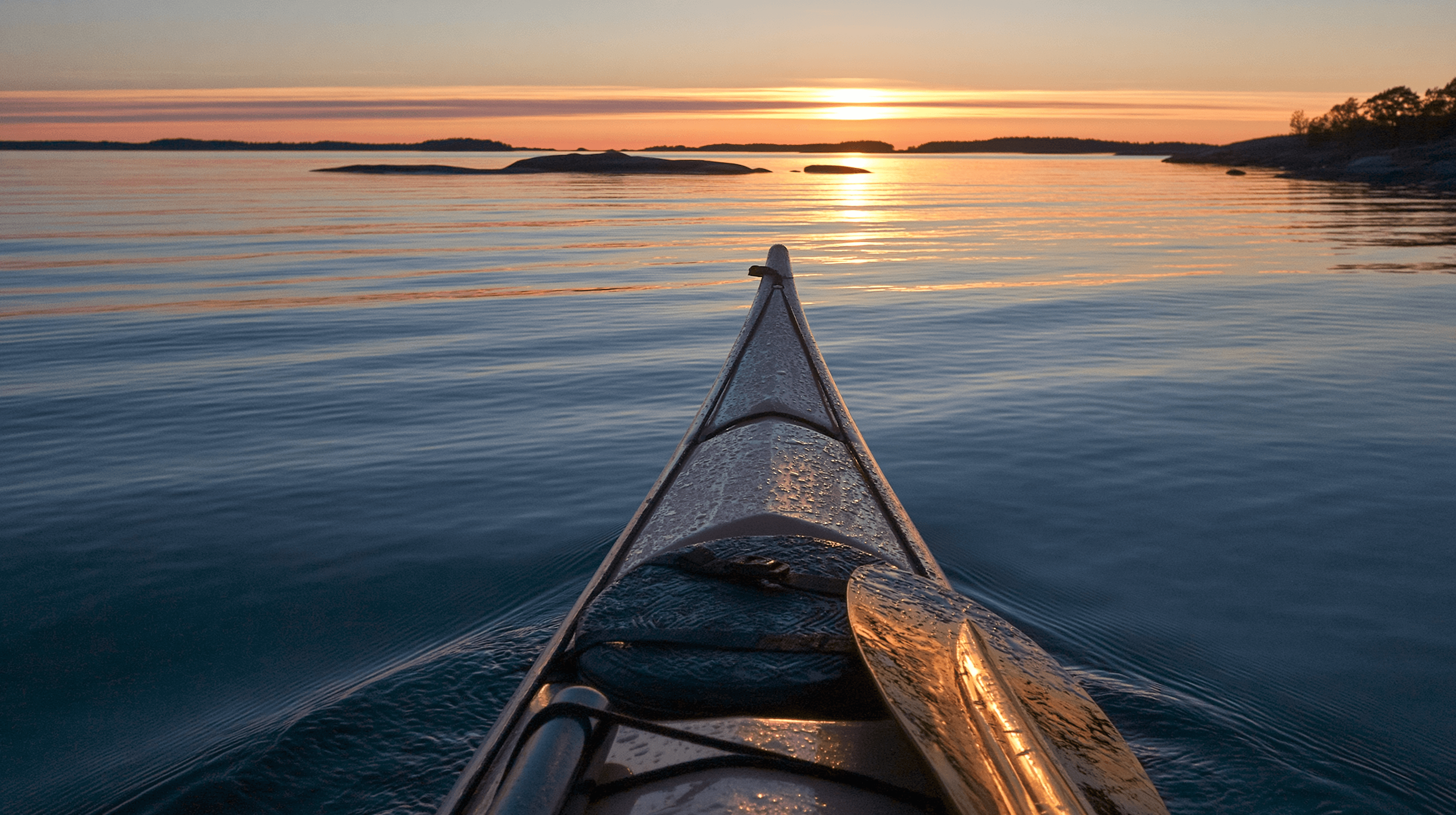 Kayak facing sunset over open archipelago water